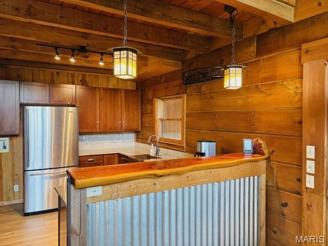 19125 County Road 1220, St James, MO 65559 - kitchen with freestanding refrigerator, a sink, wood walls, light wood-style floors, and rail lighting