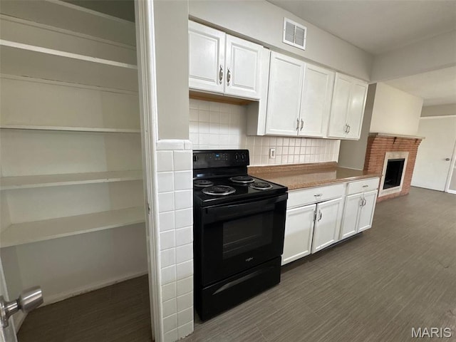 2355 Redman Rd, Saint Louis, MO 63136 - kitchen featuring black / electric stove, white cabinetry, tasteful backsplash, a brick fireplace, and dark wood-type flooring