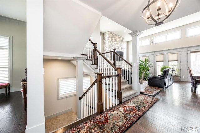 7032 Koufax Ct, Edwardsville, IL 62025 - staircase with ornate columns, a chandelier, wood-type flooring, a high ceiling, and recessed lighting