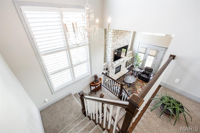 7032 Koufax Ct, Edwardsville, IL 62025 - stairs featuring carpet, a glass covered fireplace, a chandelier, baseboards, and a high ceiling