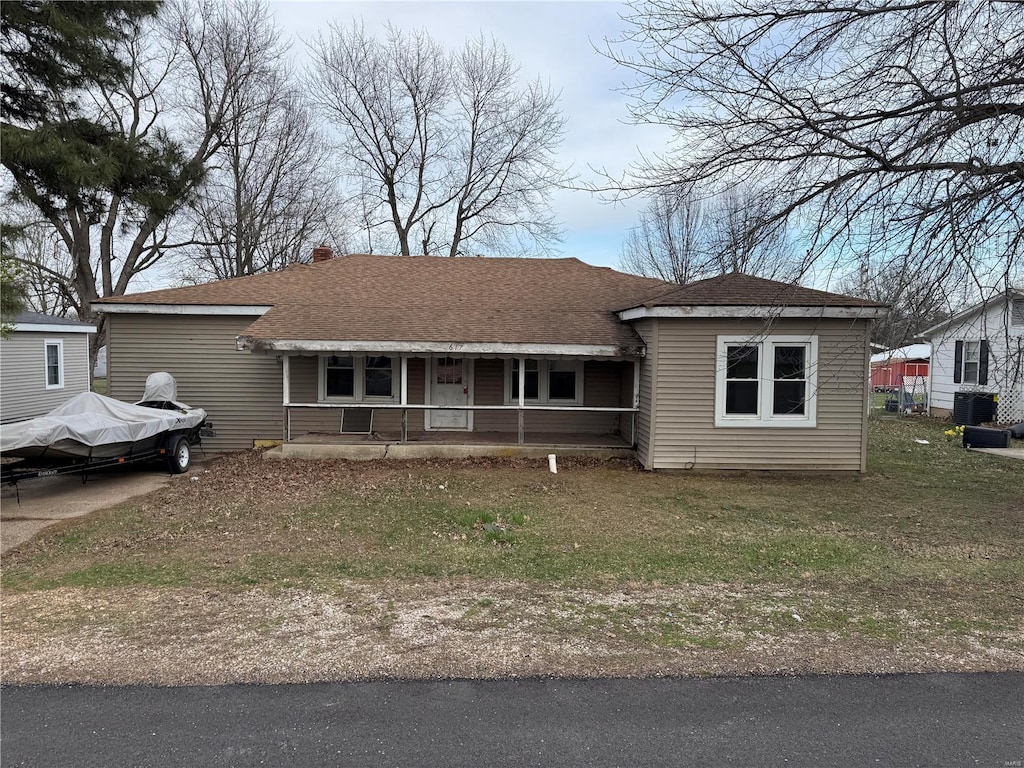 view of front of house featuring a porch, cooling unit, roof with shingles, and a front yard