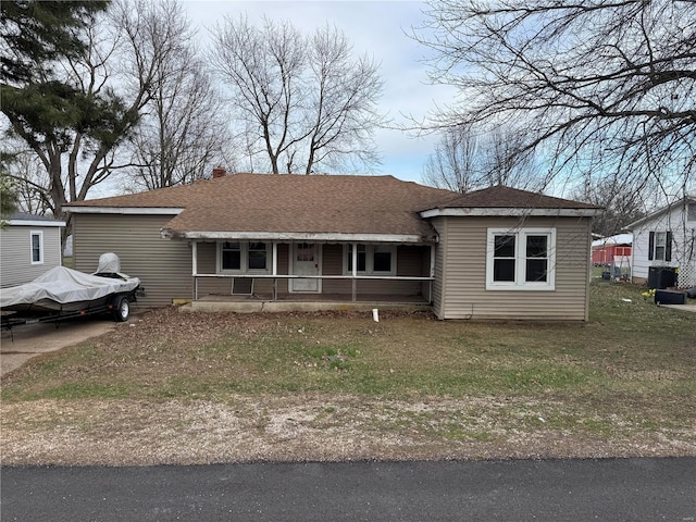 view of front of house featuring a porch, cooling unit, roof with shingles, and a front yard