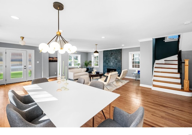 7825 Lafon Pl, Saint Louis, MO 63130 - dining space with ornamental molding, stairs, light wood-style flooring, baseboards, and a large fireplace