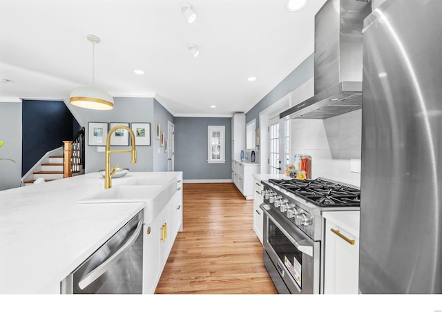 7825 Lafon Pl, Saint Louis, MO 63130 - kitchen with stainless steel appliances, wall chimney range hood, a sink, crown molding, and white cabinets