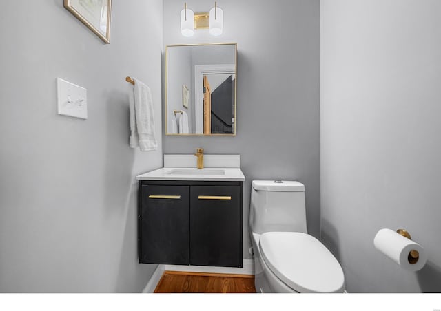 7825 Lafon Pl, Saint Louis, MO 63130 - half bath featuring toilet, wood finished floors, and vanity