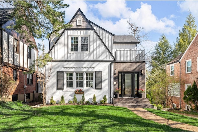 7825 Lafon Pl, Saint Louis, MO 63130 - tudor house featuring a balcony, board and batten siding, brick siding, a front yard, and roof with shingles