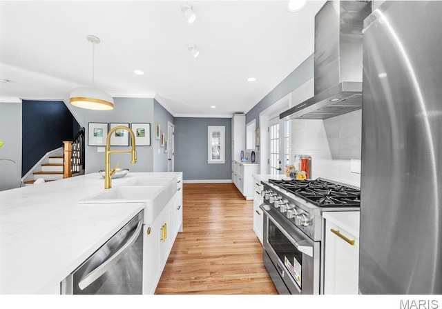 7825 Lafon Pl, Saint Louis, MO 63130 - kitchen featuring stainless steel appliances, wall chimney exhaust hood, a sink, crown molding, and white cabinetry