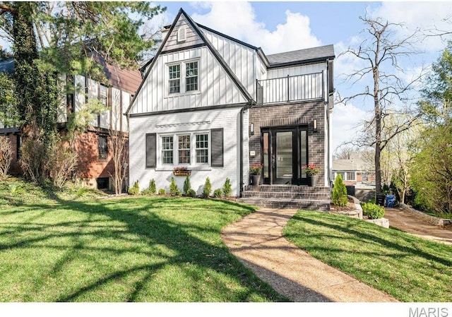 7825 Lafon Pl, Saint Louis, MO 63130 - tudor home featuring a balcony, brick siding, board and batten siding, and a front lawn