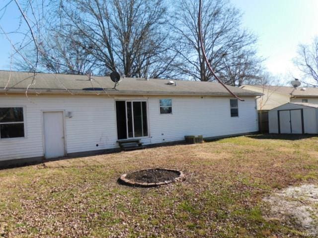 back of property with a storage unit, entry steps, an outdoor structure, and a yard