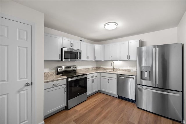 7600 Triwoods Dr Unit G, Saint Louis, MO 63119 - kitchen featuring appliances with stainless steel finishes, a sink, light wood-style flooring, and light stone counters