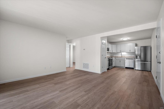 7600 Triwoods Dr Unit G, Saint Louis, MO 63119 - unfurnished living room with wood finished floors, baseboards, and a sink