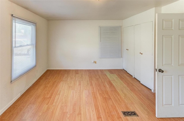 unfurnished bedroom with light wood-style floors, a closet, and baseboards