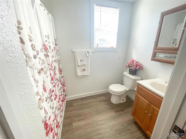 bathroom with wood finished floors, toilet, vanity, baseboards, and a shower with shower curtain