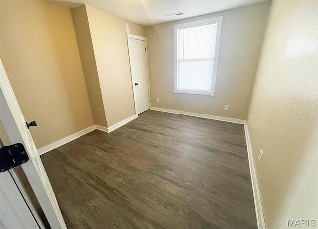 empty room with dark wood-style floors and baseboards