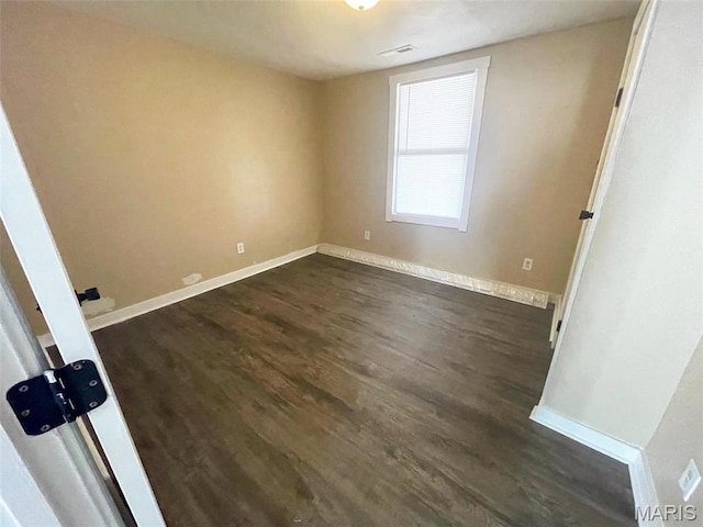 empty room with dark wood-type flooring and baseboards