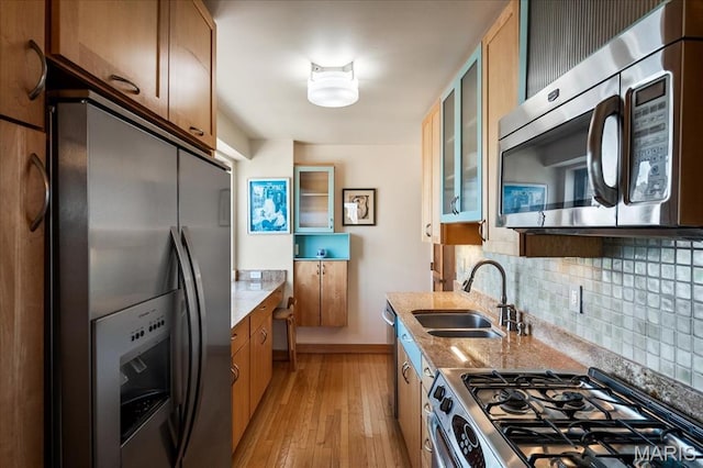4466 W Pine Blvd Unit 15C, Saint Louis, MO 63108 - kitchen with appliances with stainless steel finishes, a sink, backsplash, light wood-style flooring, and glass insert cabinets