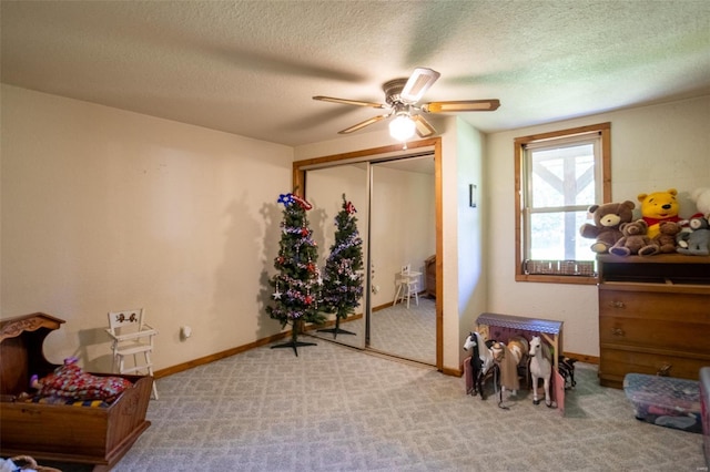 carpeted bedroom with a closet, a textured ceiling, ceiling fan, and baseboards