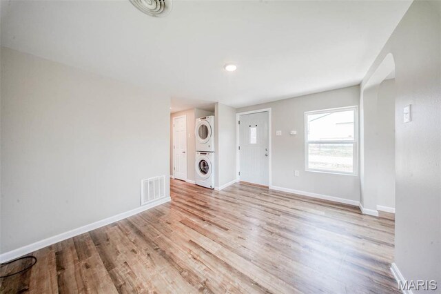 713 N Oak St, Salem, MO 65560 - unfurnished living room featuring stacked washing machine and dryer, light wood-style flooring, baseboards, and arched walkways