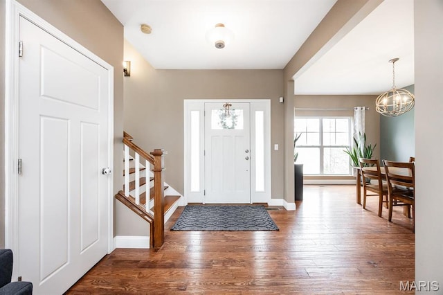 entrance foyer with a chandelier, hardwood / wood-style flooring, stairs, and baseboards
