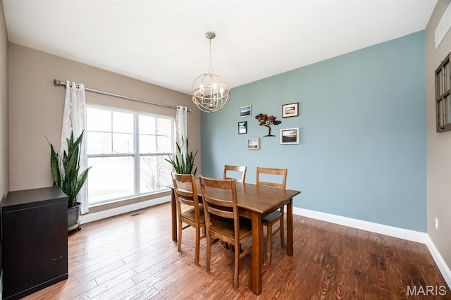 dining area featuring a chandelier, wood finished floors, and baseboards