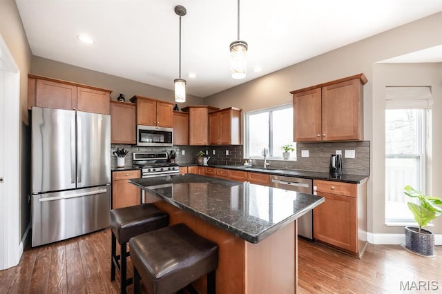 kitchen featuring appliances with stainless steel finishes, a sink, wood finished floors, decorative backsplash, and recessed lighting
