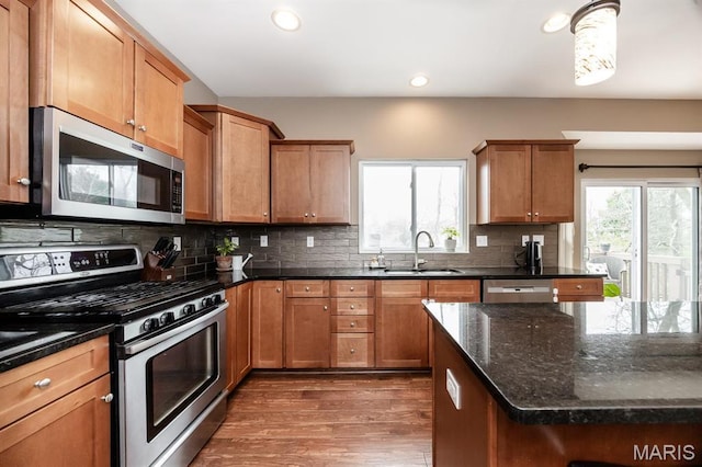 kitchen with appliances with stainless steel finishes, a sink, dark wood-type flooring, recessed lighting, and backsplash