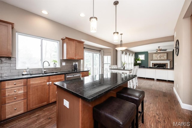 kitchen with a sink, a center island, open floor plan, dishwasher, and tasteful backsplash