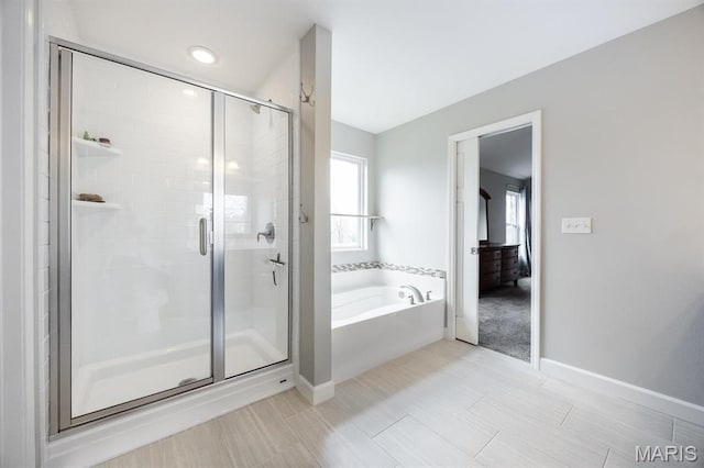 bathroom with a bath, a shower stall, and baseboards