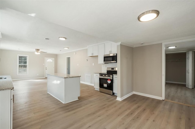 1107 Hickory St, Poplar Bluff, MO 63901 - kitchen featuring appliances with stainless steel finishes, baseboards, crown molding, white cabinets, and light wood-style flooring