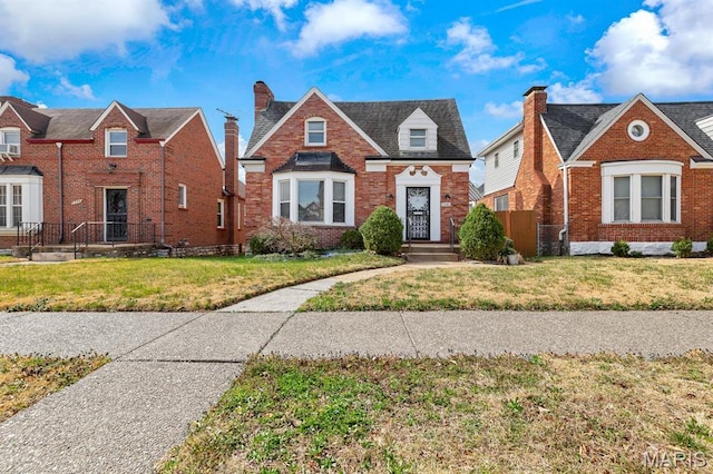 view of front of house with a front yard, brick siding, and a chimney