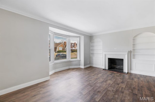 unfurnished living room featuring dark wood-type flooring, built in features, crown molding, baseboards, and a fireplace