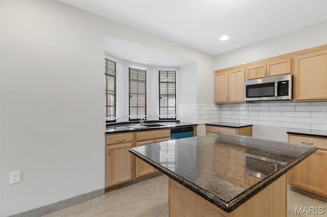 kitchen featuring stainless steel microwave, light brown cabinetry, dishwashing machine, a sink, and decorative backsplash