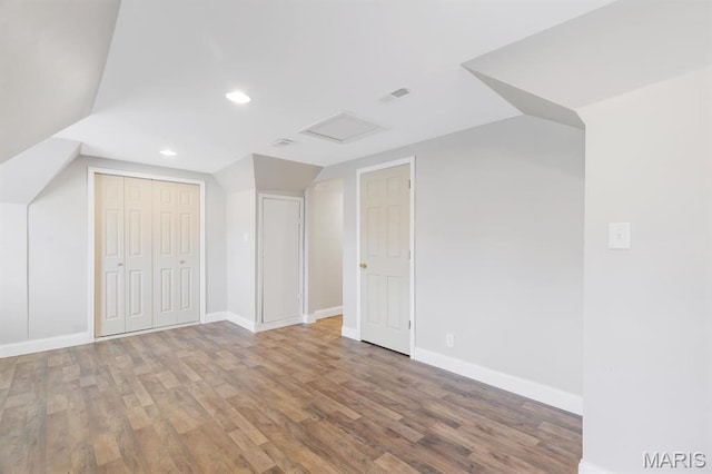 additional living space featuring wood finished floors, baseboards, recessed lighting, lofted ceiling, and attic access