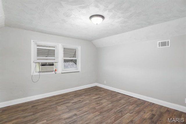 additional living space featuring vaulted ceiling, wood finished floors, baseboards, a textured ceiling, and cooling unit