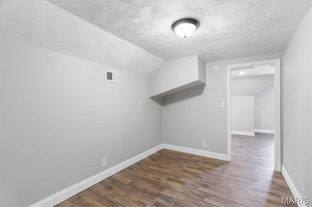 additional living space with vaulted ceiling, dark wood-style flooring, and baseboards