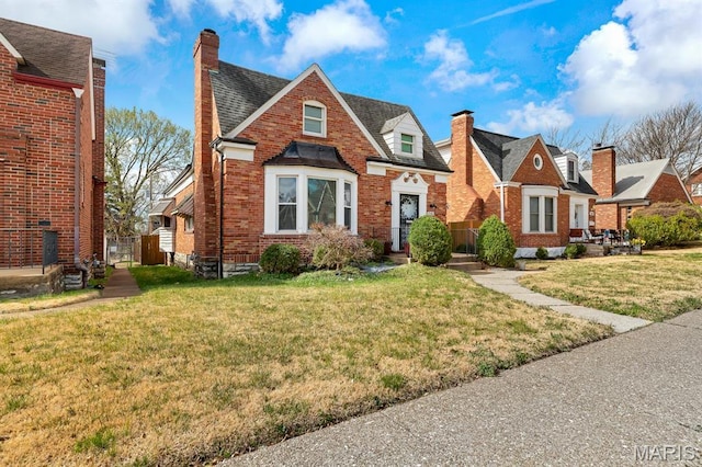 view of front of property with a chimney, brick siding, and a front yard