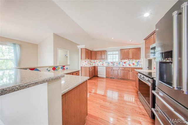 1106 Grandsir Ave, Rolla, MO 65401 - kitchen featuring appliances with stainless steel finishes, vaulted ceiling, tasteful backsplash, light wood-style floors, and light stone countertops