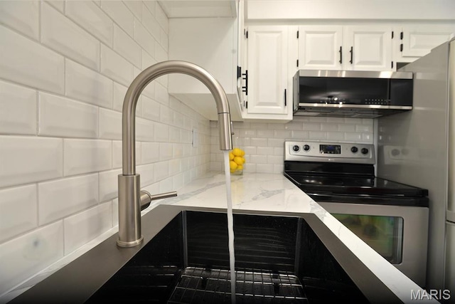1680 Herault Pl Unit F, Saint Louis, MO 63125 - kitchen featuring appliances with stainless steel finishes, white cabinetry, decorative backsplash, light stone counters, and a sink