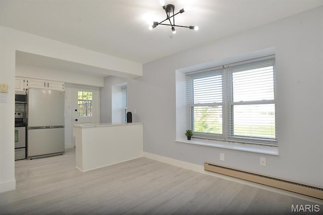 1680 Herault Pl Unit F, Saint Louis, MO 63125 - spare room featuring a baseboard radiator, a chandelier, light wood-type flooring, and baseboards
