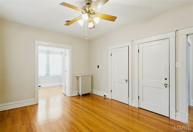 unfurnished bedroom featuring radiator, light wood-style floors, and baseboards