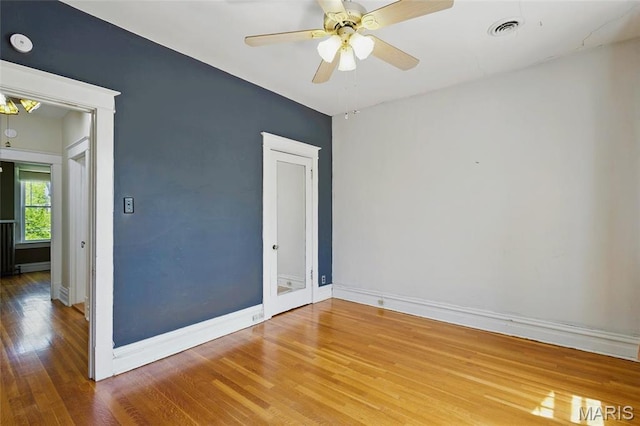 spare room featuring wood finished floors, baseboards, a smoke detector, and a ceiling fan