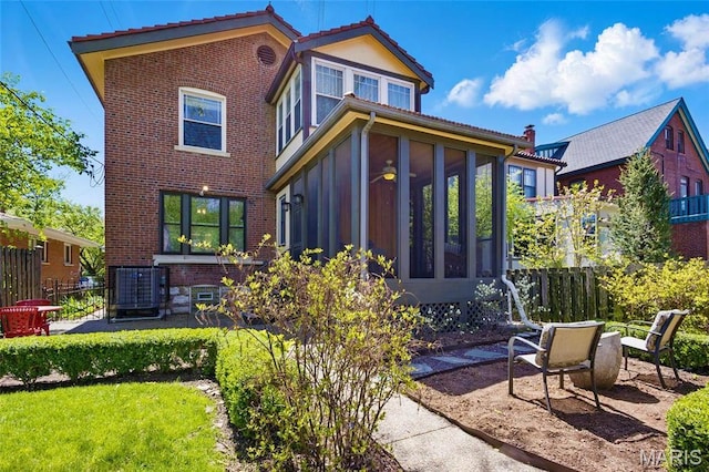 back of property with a sunroom, central air condition unit, fence, and a patio area