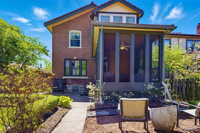 view of front of house with a sunroom, fence, a tiled roof, and brick siding