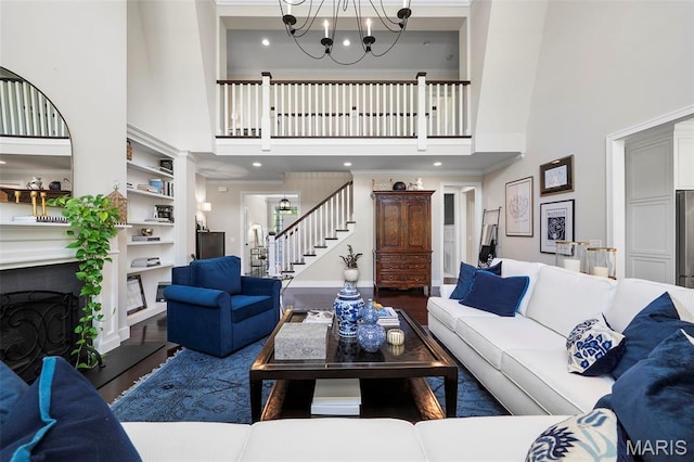 1178 Turnberry Dr, Innsbrook, MO 63390 - living room featuring a towering ceiling, stairs, a chandelier, built in shelves, and crown molding