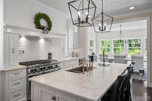 1178 Turnberry Dr, Innsbrook, MO 63390 - kitchen with range with two ovens, a chandelier, a sink, white cabinetry, and a center island with sink