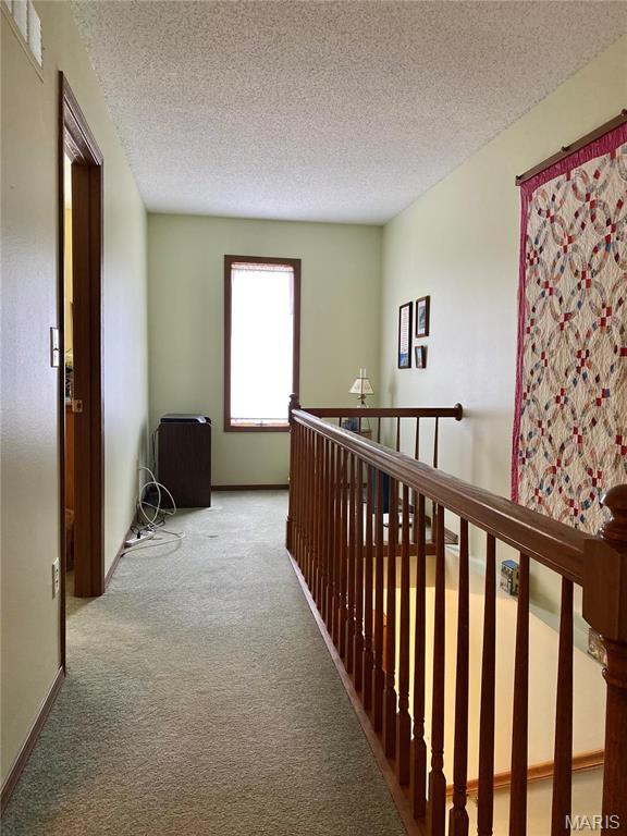 2128 Friendship Ct, Florissant, MO 63031 - corridor featuring carpet, a textured ceiling, and an upstairs landing
