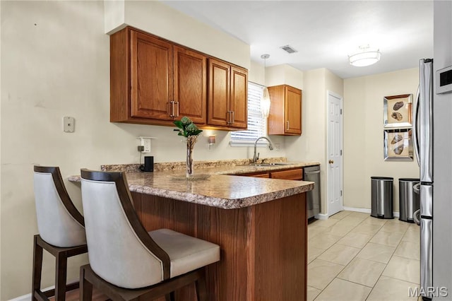 3110 Autumn Shores Dr, Maryland Heights, MO 63043 - kitchen featuring a sink, a peninsula, appliances with stainless steel finishes, a kitchen breakfast bar, and brown cabinets