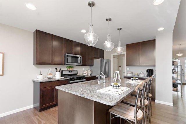 22712 Danison Dr, Warrenton, MO 63383 - kitchen with appliances with stainless steel finishes, a sink, baseboards, a breakfast bar, and recessed lighting