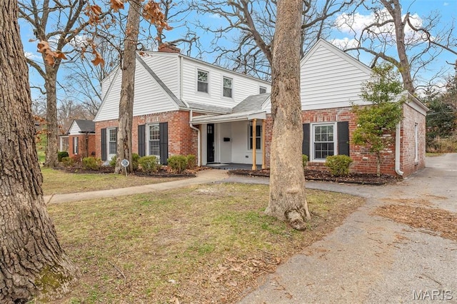 83 Chafford Woods, Saint Louis, MO 63144 - view of front facade featuring brick siding, a chimney, a front lawn, and covered porch