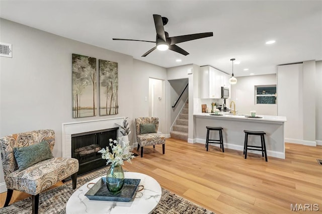 83 Chafford Woods, Saint Louis, MO 63144 - living area featuring a fireplace, light wood finished floors, stairway, ceiling fan, and recessed lighting